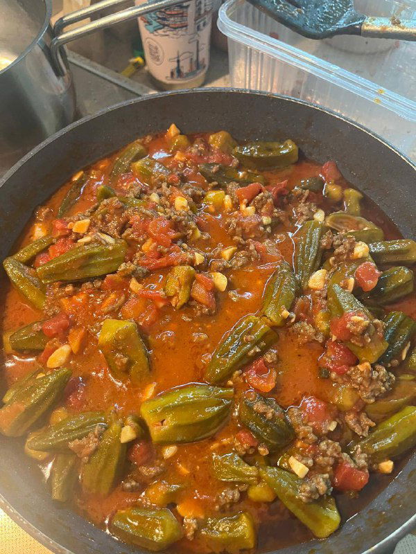 Готовое блюдо бамия с томатным соусом и фаршем в сковороде — насыщенный соус, равномерно покрывающий стручки, видна готовность к подаче.