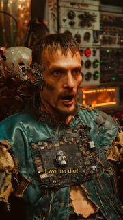 Персонаж в технической мастерской с панелями и проводкой на заднем плане — атмосфера лаборатории и ремесла в мире фильма.