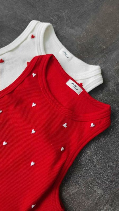 Две майки (белая и красная) на плоской поверхности, красная с маленькими сердечками — пример текстур и принтов в красно‑белой палитре.