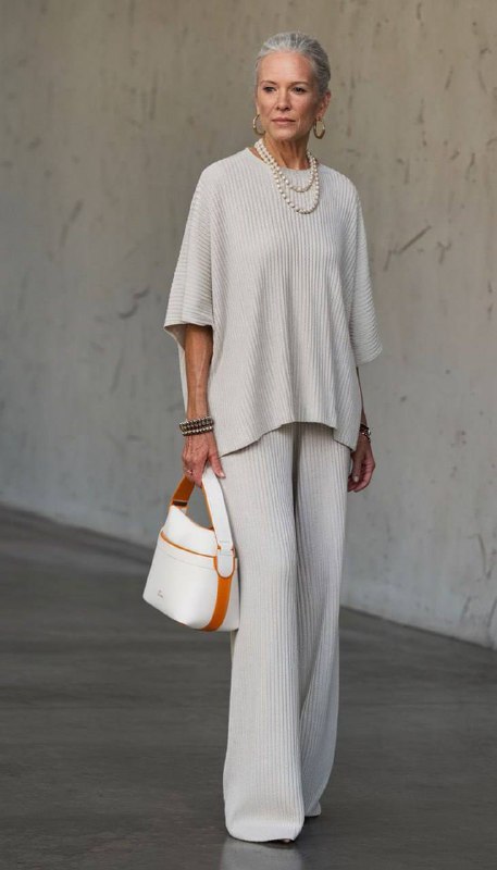 Пожилая женщина в монохроме: светлый трикотажный комплект свободного кроя, минималистичный и комфортный вариант для родителя на мероприятии.