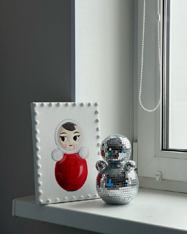 Интерьерный кадр на подоконнике: декоративная панель с изображением неваляшки и зеркальная неваляшка‑диско, сочетание арт‑объекта и повседневности.