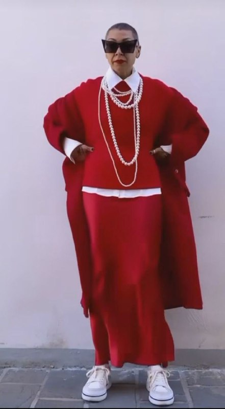 Целостный образ в красных тонах: длинное пальто, юбка и многослойные жемчужные нити — сочетание игры и защиты в стиле.