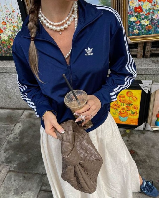 Девушка в тёмно-синей олимпийке Adidas с многорядным жемчугом, сумка и стакан кофе в руках, городской уличный кадр, casual-детали.