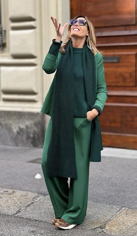 Женщина в светло‑зелёном пальто и тёмно‑зелёном шарфе на городской улице — пример сочетания холодных и тёплых нот в образе.