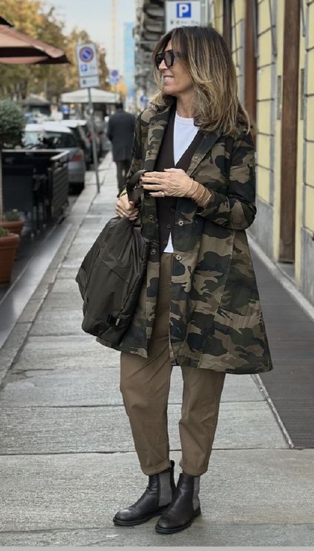 Камуфляжная парка и нейтральные коричнево‑оливковые брюки на прогулке — пример хаки и милитари как способа показать защиту и структуру образа.