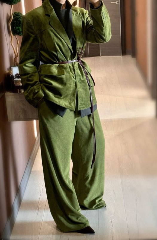 Инфлуенсер в мягком бархатистом зелёном костюме с поясом — пример тёплого зелёного, который создаёт ощущение уюта и внутренней опоры в образе.