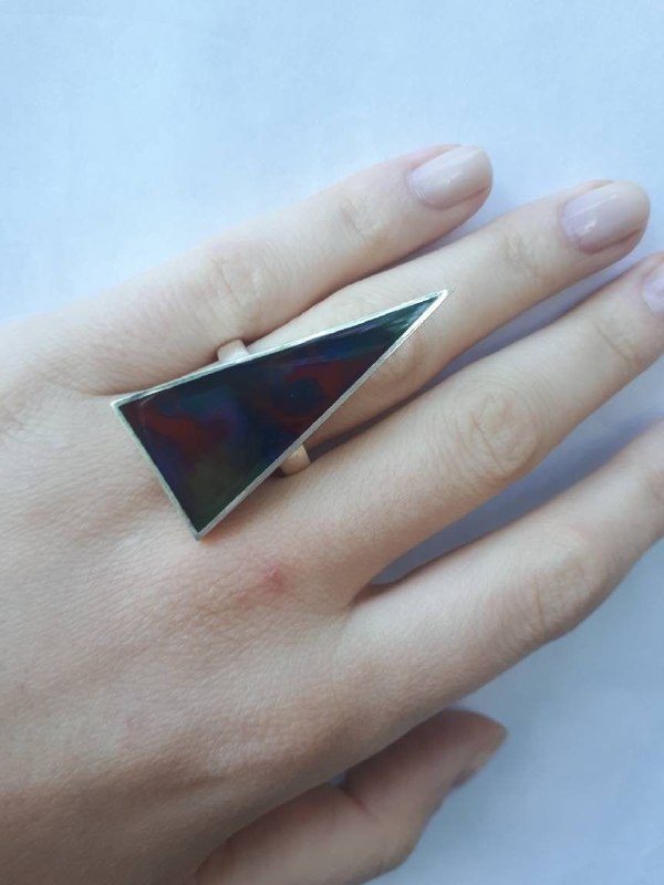 Крупный треугольный перстень на пальце крупным планом; металлическая геометрия как акцент, символизирующий направление и внутренний импульс.