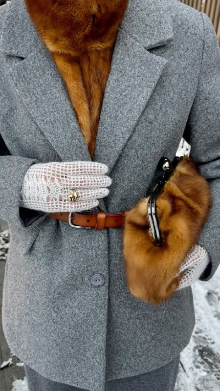 Серое пальто с глубоким коричневым меховым воротником и меховой муфтой в руке, сочетание структуры ткани и меха в городском образе.