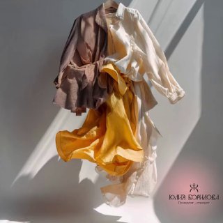 Летящие в воздухе вещи на нейтральном фоне: блузка, пиджак и жёлтое платье в мягком свету — эстетическая визуализация идеи гардероба как отражения состояния.