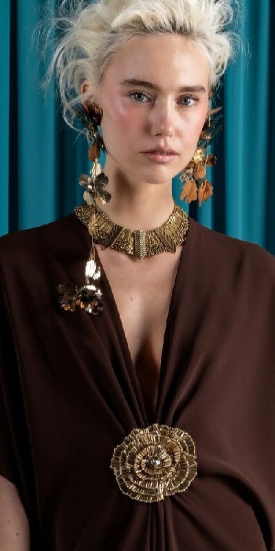 Портрет с массивными металлическими украшениями и крупной брошей-подвеской, акцент на золотистых деталях и их роли как центрального элемента образа.