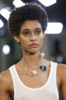 Модель с минималистичным топом и тонкими металлическими ожерельями, показывающая, как даже простые элементы могут создать ритм и законченный образ.