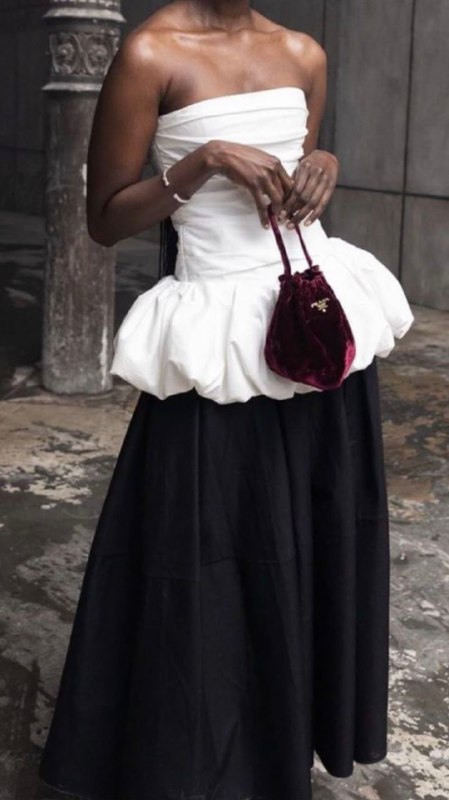 Крупный план тёмной кожи и белой баски на платье: объём у низа туловища создаёт женственный силуэт и притягивает взгляд к зоне бёдер.