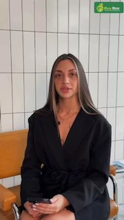 Женщина в чёрном пиджаке сидит на стуле на фоне светлой плиточной стены; в правом верхнем углу кадра виден зелёный логотип BuyBox — превью к видео с ведущей канала.