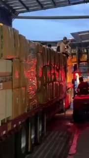 Погрузчик поднимает стопки упакованных коробок на прицеп: процесс спрессованных и упакованных отправлений на складе BuyBox в ночное время.