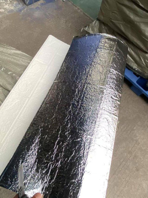 Рулон самоклеящейся панели с защитной пленкой и рядом видна белая лицевая сторона панели; демонстрация упаковки и лицевой поверхности.