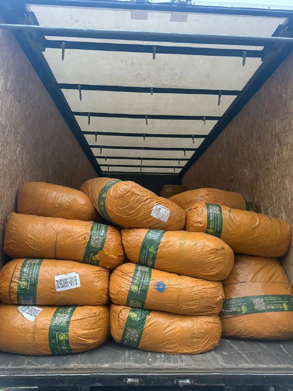 Открытый фургон с упакованными в жёлтую плёнку бандеролями и мешками — привозные партии товаров, подготовленные к проверке и упаковке.