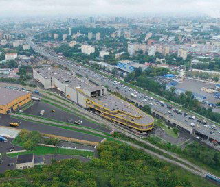 Аэрофото производственно‑логистического парка с эстакадой и автодорогой, показывающее взаимосвязь комплекса с городской транспортной инфраструктурой.