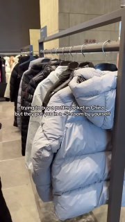 Ряд пуховиков и курток на вешалке в магазине; кадр из ролика или сторис про концепцию примерочных с имитацией зимних условий и снегопада.