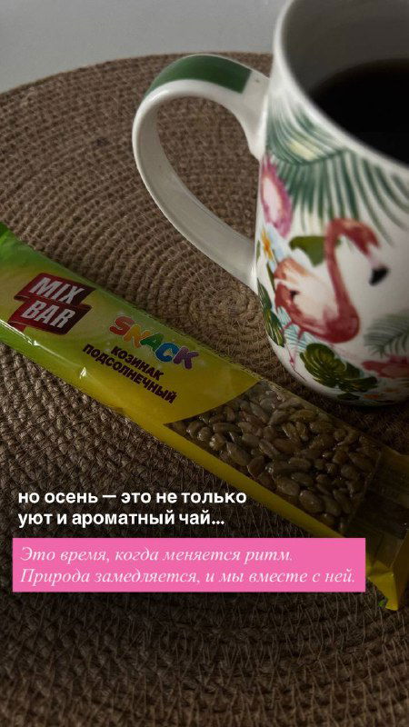 Чашка чая с рисунком фламинго и батончик на плетёной подложке у окна — уютный кадр, подчёркивающий тёплую атмосферу и комфорт осенних вечеров в домашних уходовых ритуалах.