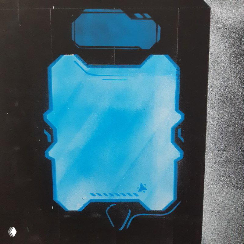 Деталь интерьера: элемент панели с голубым подсвеченным полигональным рисунком, часть декора арены и рабочие материалы рядом.