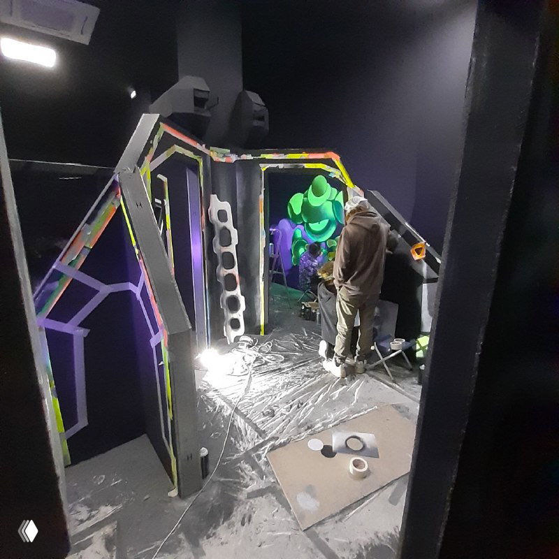 Рабочая сцена внутри арены: монтажные леса и элементы проходов, художник за работой, антискользящая защита пола и освещение.