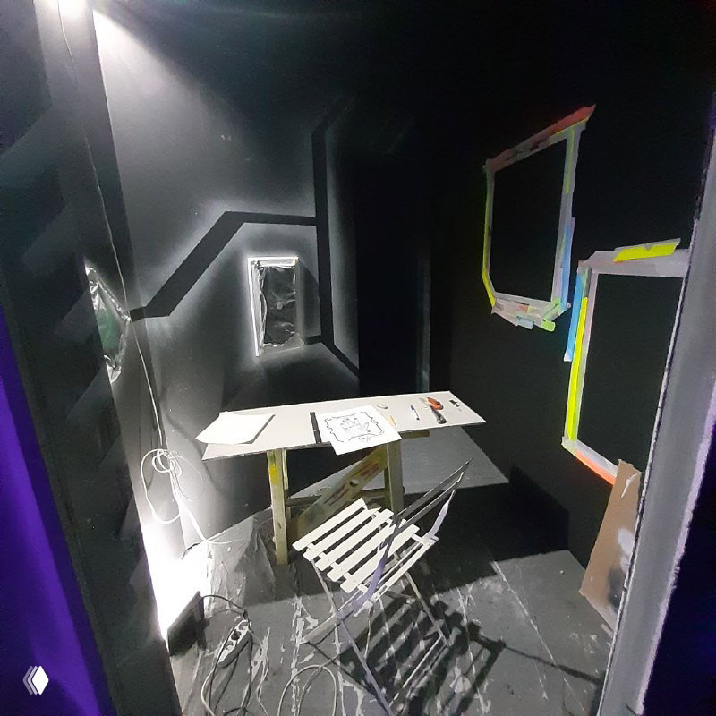 Узкий проход с настенными эскизами и лестницей, временные покрытия на полу и рабочие элементы подготовки пространства под роспись.