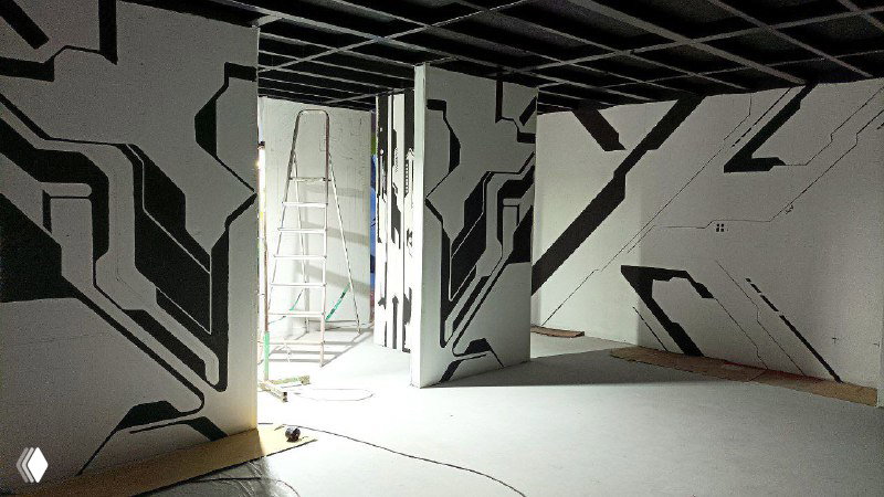Угол помещения локации VR: вид на несколько стендов с начатой чёрно‑белой росписью, защитная пленка на полу и подготовка к дальнейшей работе.
