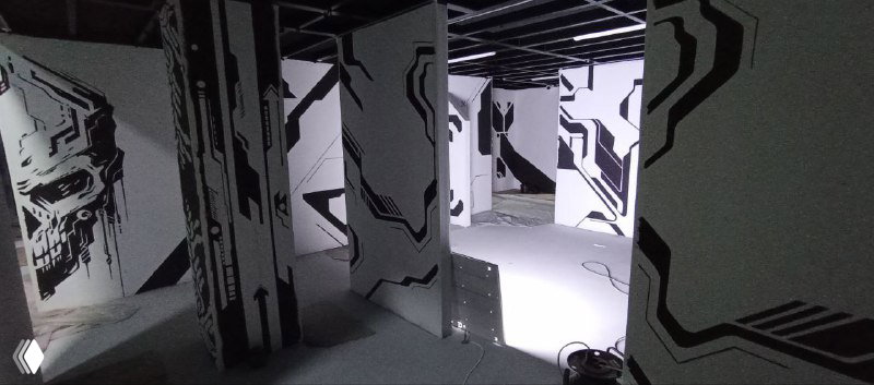 Вид с верхней точки на группу панелей с графичной росписью и полом, покрытым защитной плёнкой, отражения света создают объём.