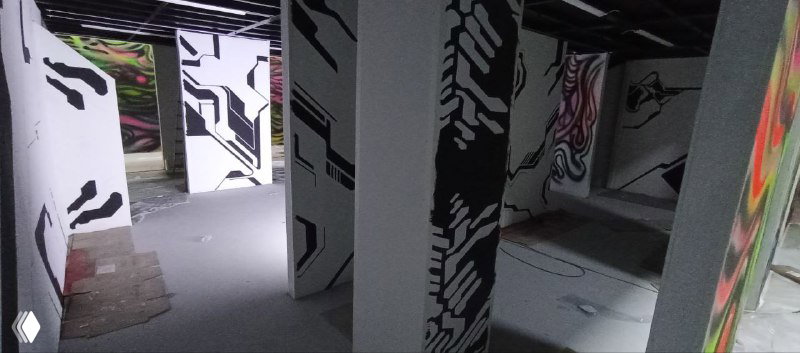 Ночная или искусственно освещённая сцена: панели с чёрно‑белыми мотивами, элементы граффити и подготовка пространства для VR‑аттракциона.