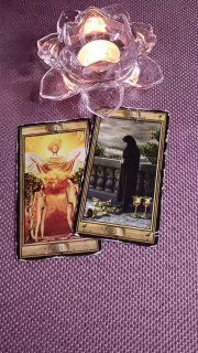 Фотография двух карт Таро на фиолетовой ткани рядом с подсвечником в виде лотоса — иллюстрация расклада и атмосферы гадания и работы с бессознательным.