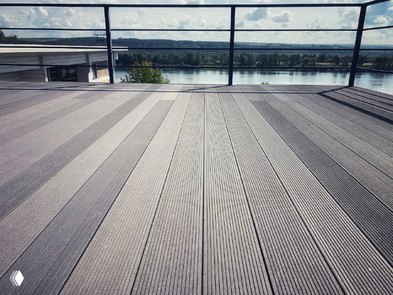 Открытая терраса с композитным настилом ProDecking на фоне реки и облачного неба, видны ровные панели и фактура доски крупным планом.