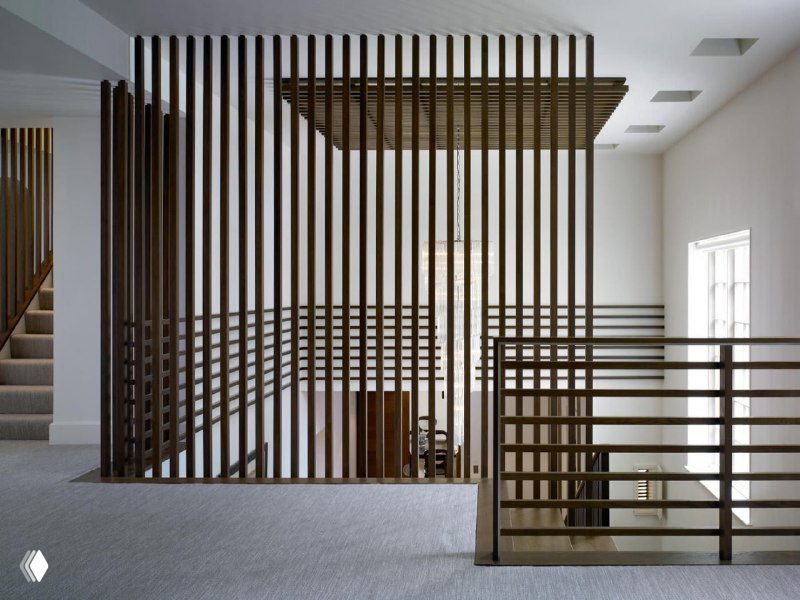 Внутренняя перегородка из тонких балясин MixDeck цвета венге, разделяющая лестничную зону и гостиную в светлом современном интерьере.