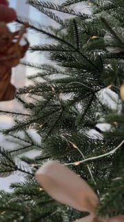 Крупный план ветви искусственной ёлки с иголками, гирляндой и бежевой игрушкой — демонстрация фактуры и естественного вида модели «Ёлушка».