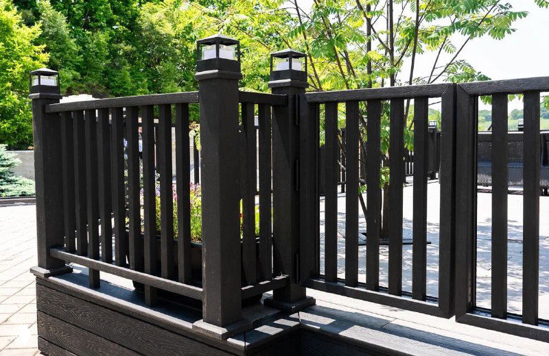 Крупный план ограждения и столбиков чёрного цвета, секция террасного ограждения из композитных материалов, вид в дневном свете.