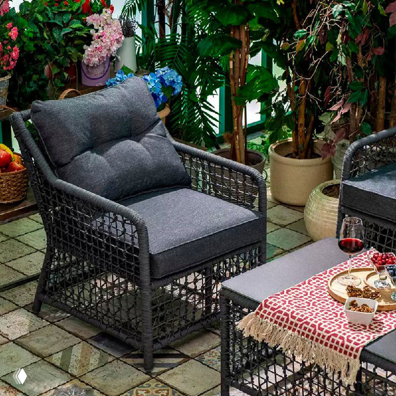 Кресло и низкий стол LUCCA с сервировкой: подушка, плетёная конструкция и декоративная салфетка на столике, образуют уютную зону отдыха.