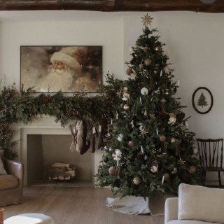 Классическая зелёная ёлка в уютной гостиной у камина, украшенная игрушками и гирляндами, интерьер в нейтральных тёплых тонах.