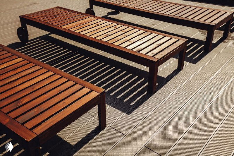 Шезлонги из дерева на фоне настила из композитной террасной доски (ДПК); контраст материалов и практичность покрытия видны на фото.