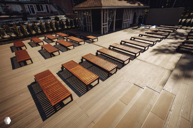 Организованная площадка со шезлонгами на просторной террасе из NewWood — ровные ряды лежаков, деревянный настил и открытое пространство.