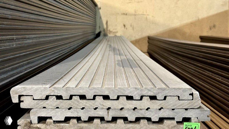 Крупный план профильных элементов ДПК, сложенных в стопку; видны замковые пазы и ребристая поверхность для террас и ограждений