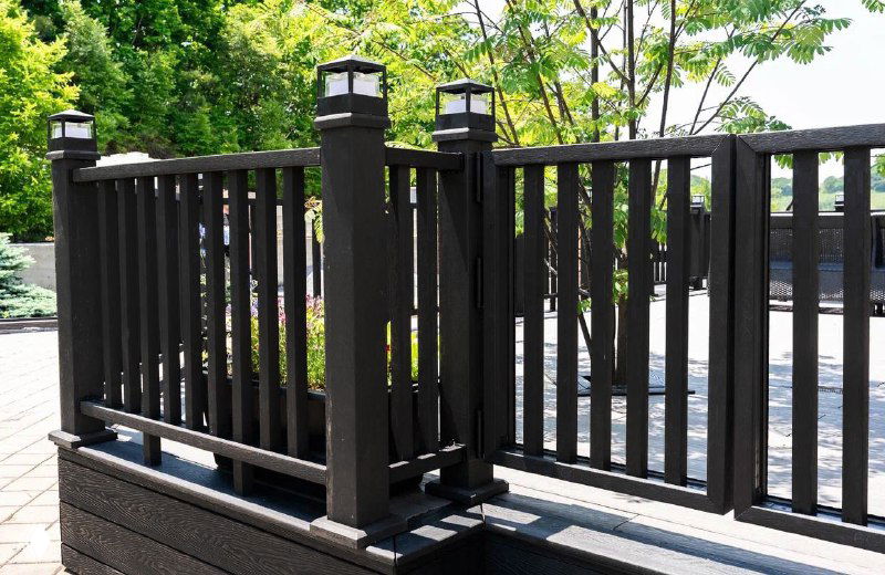 Крупный план деревянного ограждения и столбиков чёрной террасной доски Polivan — фактура доски и фитинги ограждения видны в деталях.