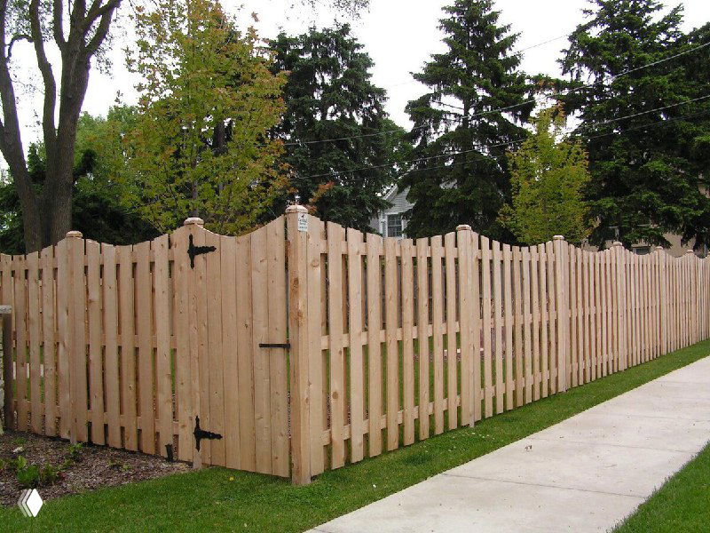 Классический деревянный штакетник светлого тона вокруг газона; показан внешний уютный и натуральный вид деревянного ограждения в саду.