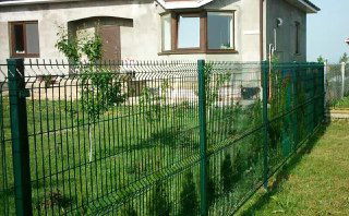 Зелёная сетка-рабица вокруг частного дома; лёгкая конструкция и невысокая приватность, пример временного ограждения на участке.