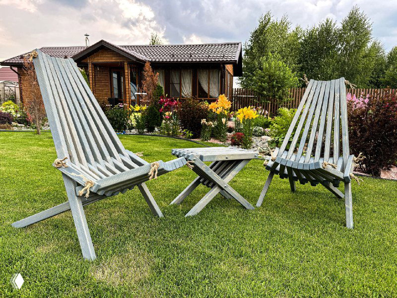 Компактная уличная мебель на газоне: складные деревянные кресла и небольшой столик, практичное и экономное решение для отдыха на даче.
