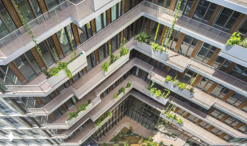 Внутренний двор современного жилого комплекса с многоуровневой террасой и зелёными насаждениями — показано архитектурное применение композитных досок на балконах и палубах.