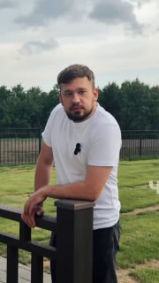 Мужчина опирается на ограждение террасы с композитной террасной доской Polivan Singaraja; на заднем плане газон и деревья.