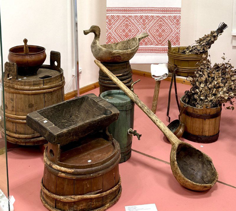 Набор старинной утвари и хозяйственных предметов: деревянные кадушки, ложки и предметы бытового обихода в экспозиции музея.