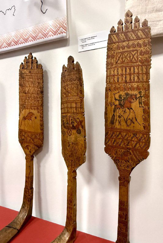 Резные деревянные лопаты с орнаментом и традиционным узором, демонстрирующие резьбу и бытовое искусство Пинежья в музее.
