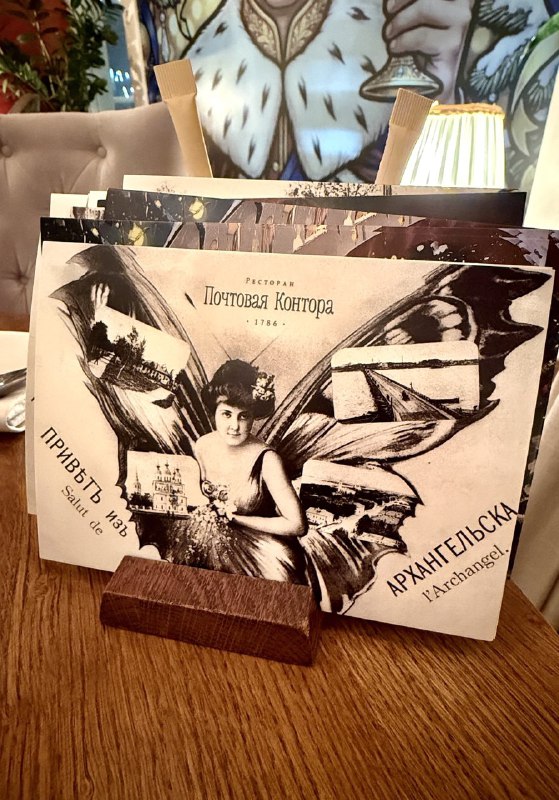 Декоративные открытки и меню на столе ресторана «Почтовая контора», снимок подчёркивает тематический стиль и историческую атмосферу заведения.