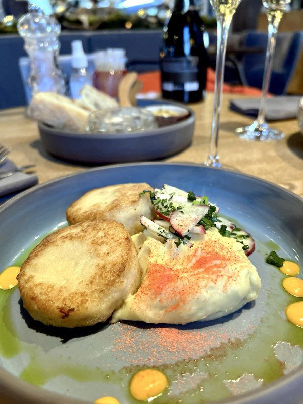 Порция из двух поджаренных изделий и соуса на тарелке, возможно сырники или котлеты, аккуратная сервировка для завтрака или лёгкого обеда.