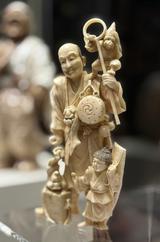 Нэцкэ и мелкие резные фигурки из слоновой кости или схожих материалов, выставленные как образец изящной миниатюры в экспозиции.